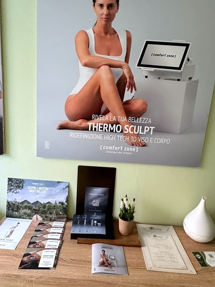 Poster Comfort Zone Thermo Sculpt, ridefinizione high tech 3D viso e corpo, sopra il mobile di Dova Estetica con le brochure dei trattamenti