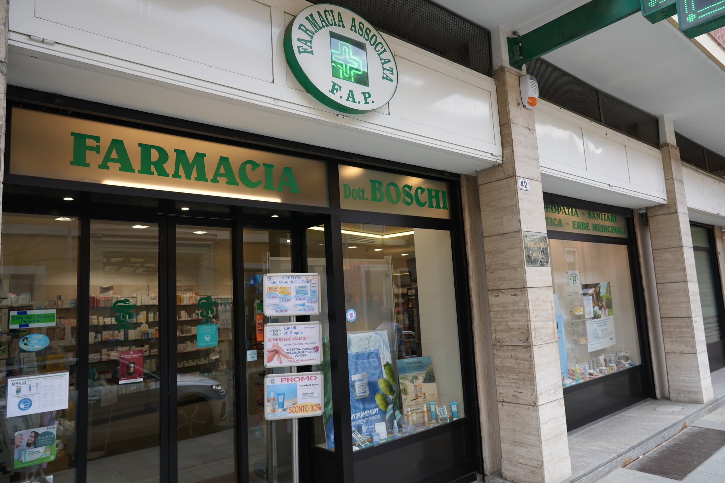 Facciata della Farmacia Dova con le vetrine, l’insegna verde Farmacia Dott. Boschi e la croce F.A.P.