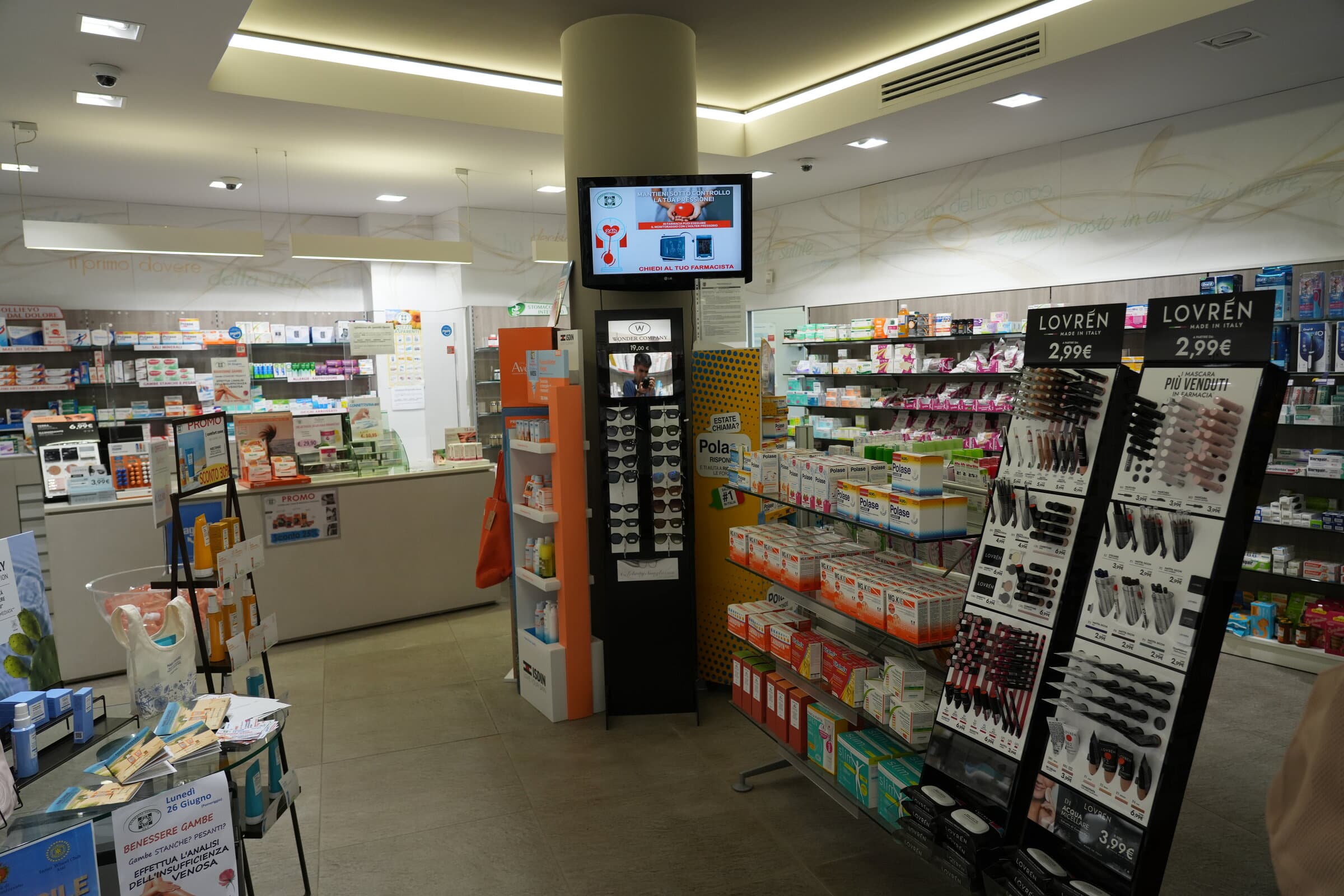 Interno della Farmacia Dova con la colonna centrale, il monitor informativo, il banco e gli scaffali