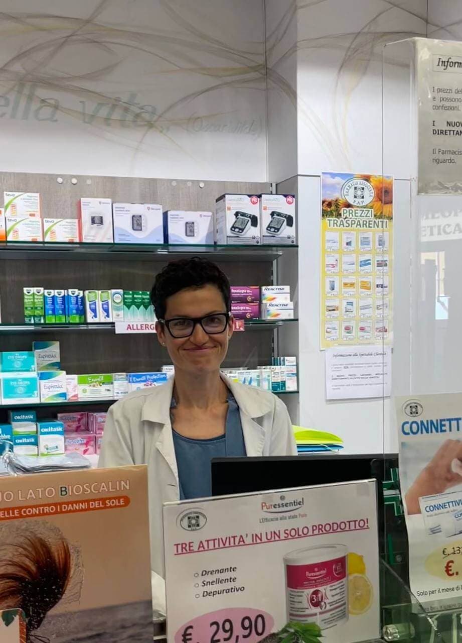 Carla Boidi, farmacista, in camice bianco dietro il banco della farmacia