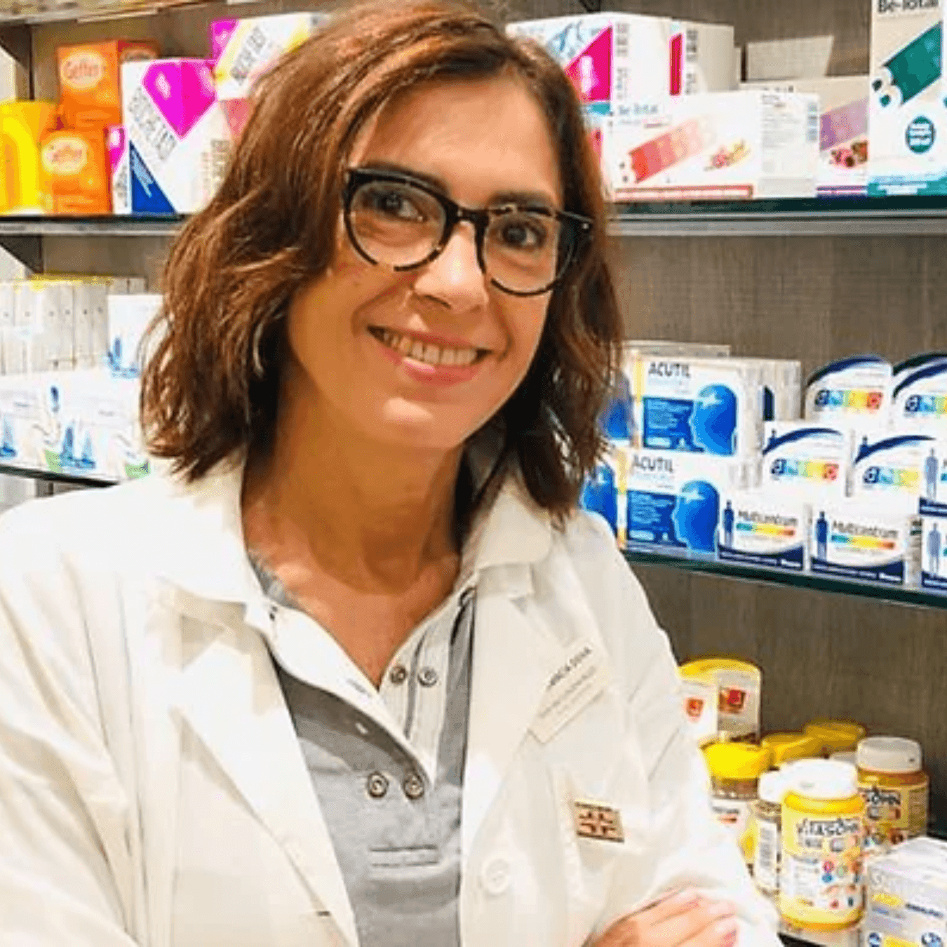 Claudia Buzzi, farmacista, sorridente in camice bianco davanti agli scaffali