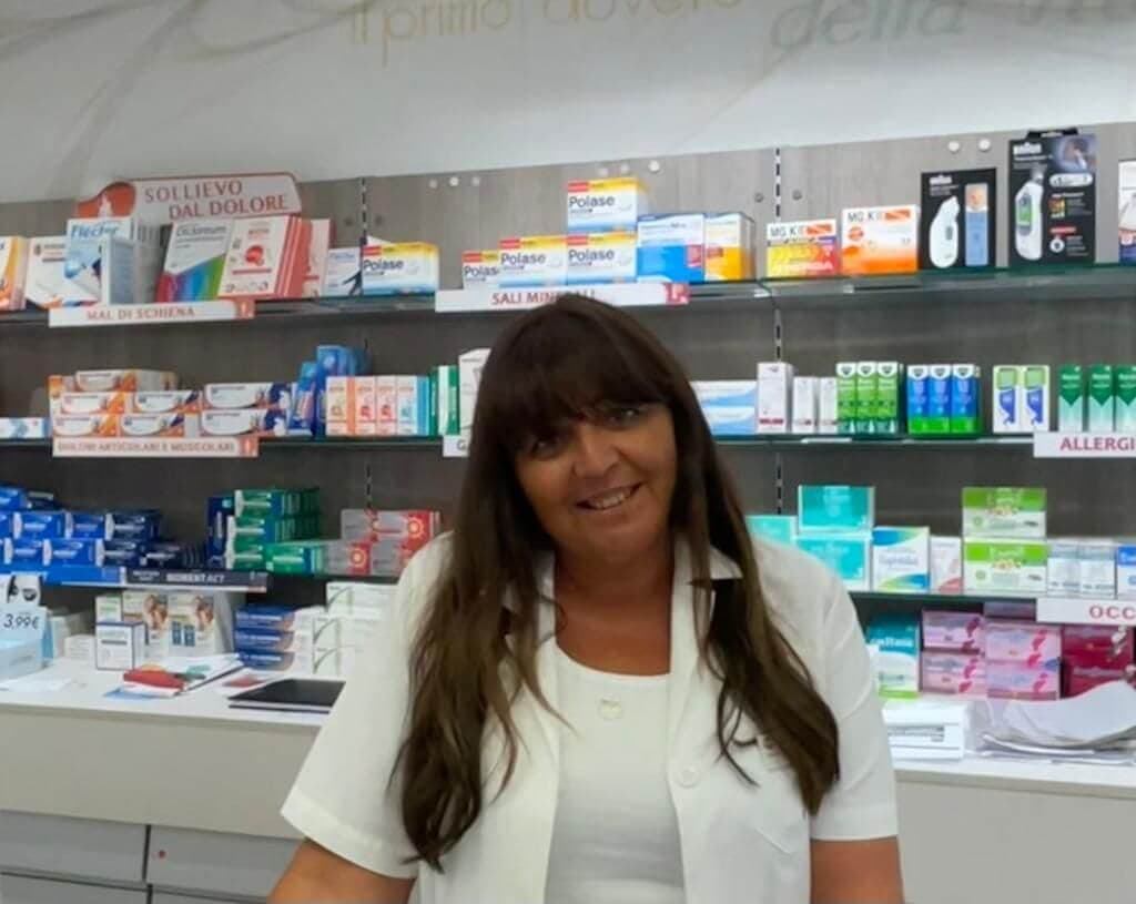 Simonetta Boschi, farmacista, in camice bianco davanti agli scaffali della farmacia