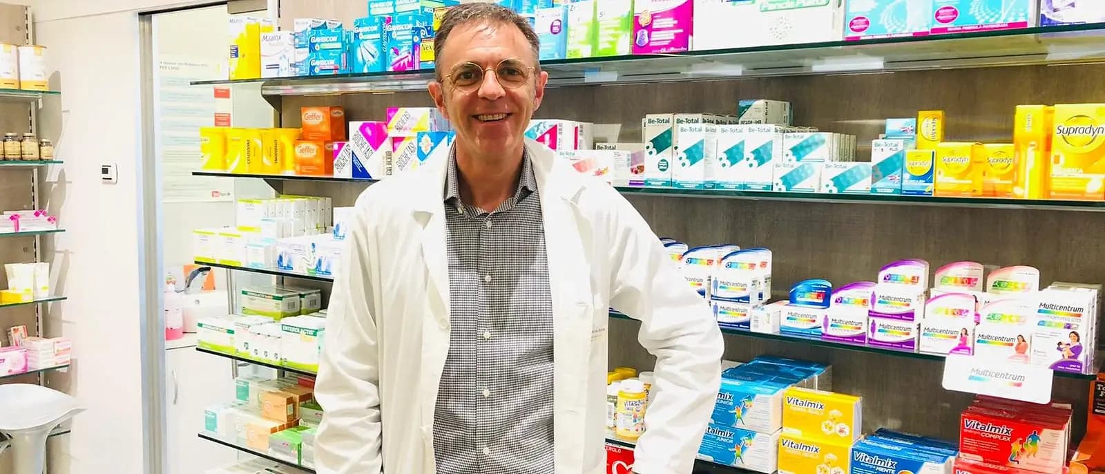 Stefano Boschi, farmacista, in camice bianco tra gli scaffali della farmacia